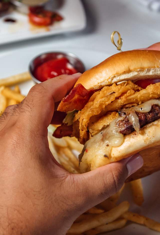 hands holding burger from Rouj Creole