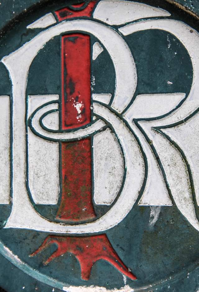 Close up of "BR" initials carved and painted on iron gate